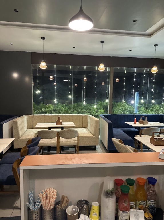 Inside Green Bean Cafe: sofas and booths under pendant lights, fairy-lit windows onto the greenery