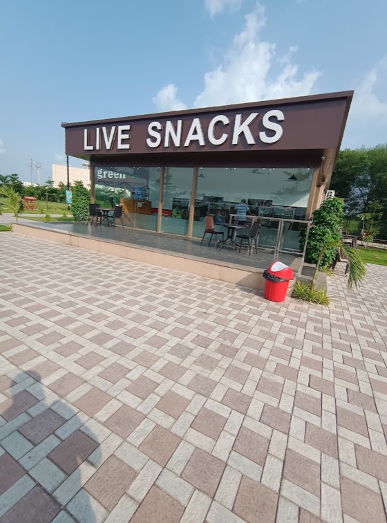 The Live Snacks counter of Manjari Gathiya Rath, glass-fronted, on the paved plaza