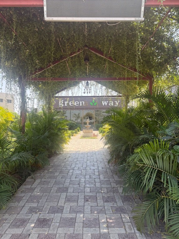 The leafy walkway to Greenway Restaurant, with the fountain and the green way sign at the end